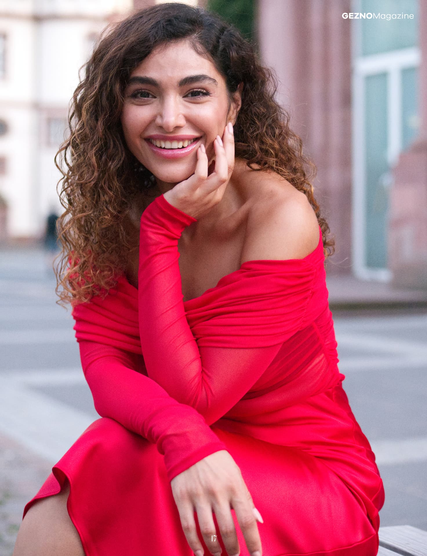 Femy Malekian lächelt im roten Off-Shoulder-Kleid